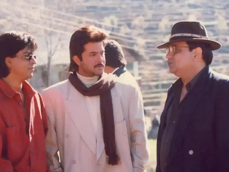 Three men in winter coats and scarves outdoors, from the Mukta Arts archive