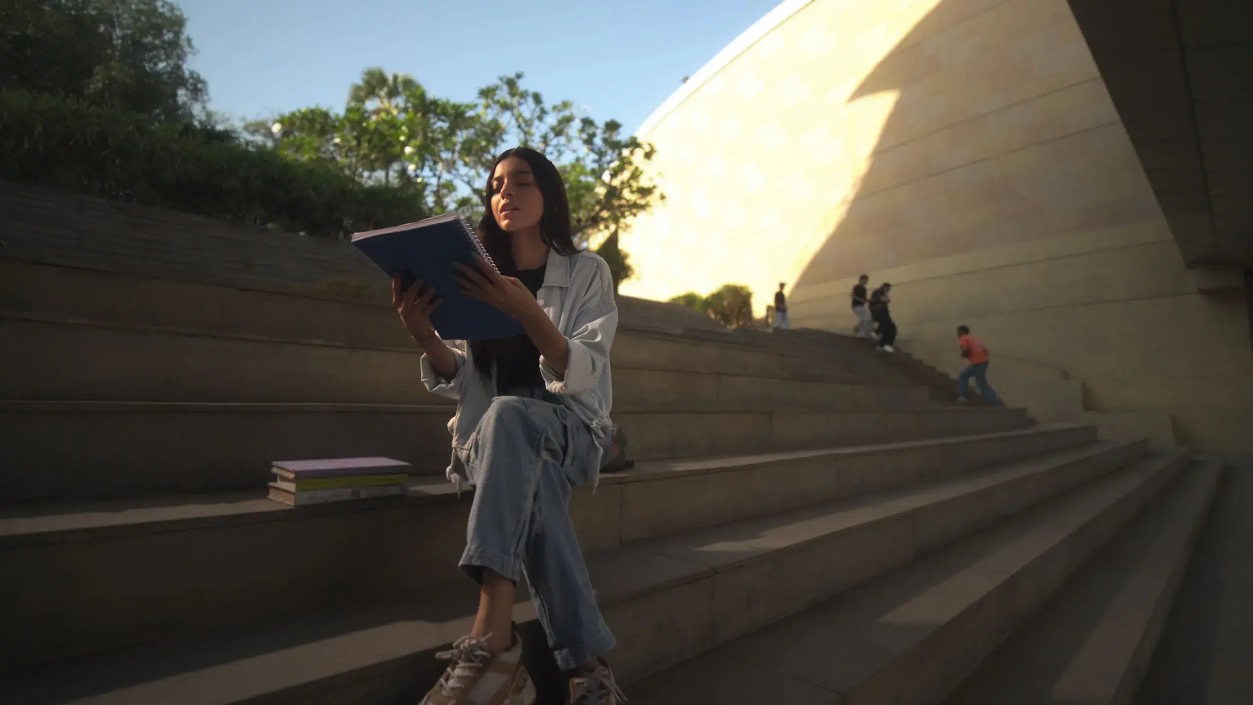 Student reading a book on the campus steps at golden hour