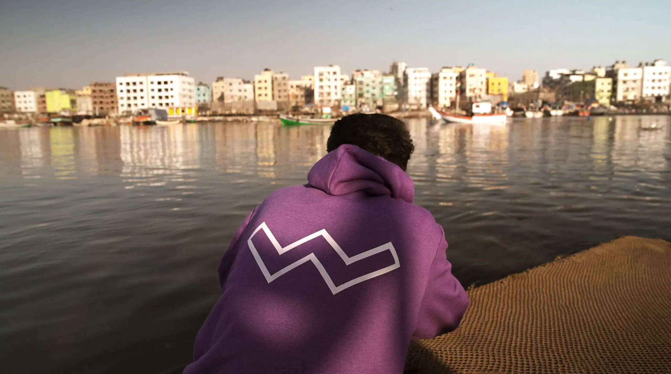 Student in a Whistling Woods hoodie looking out over a harbour