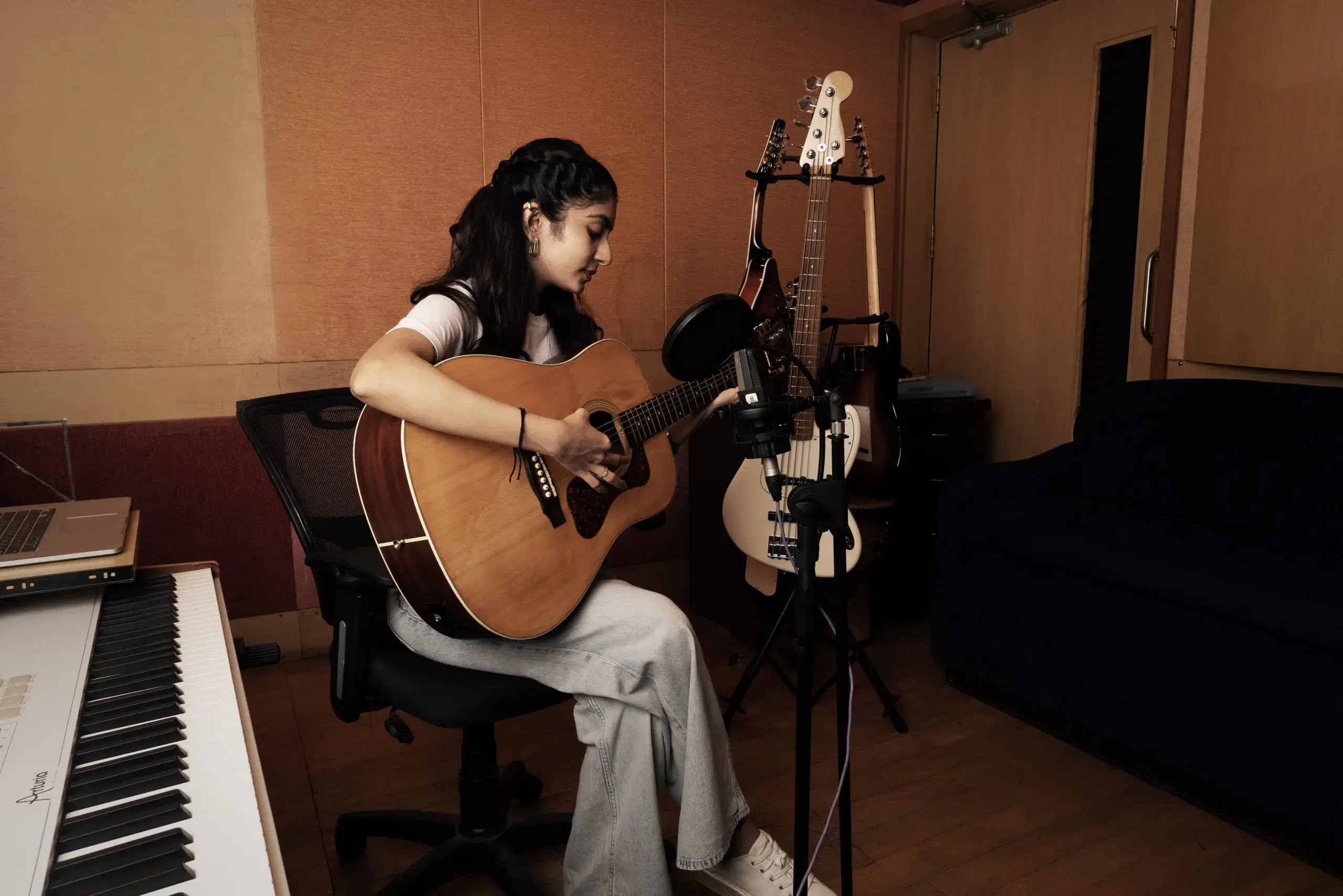 Music student playing an acoustic guitar in a studio