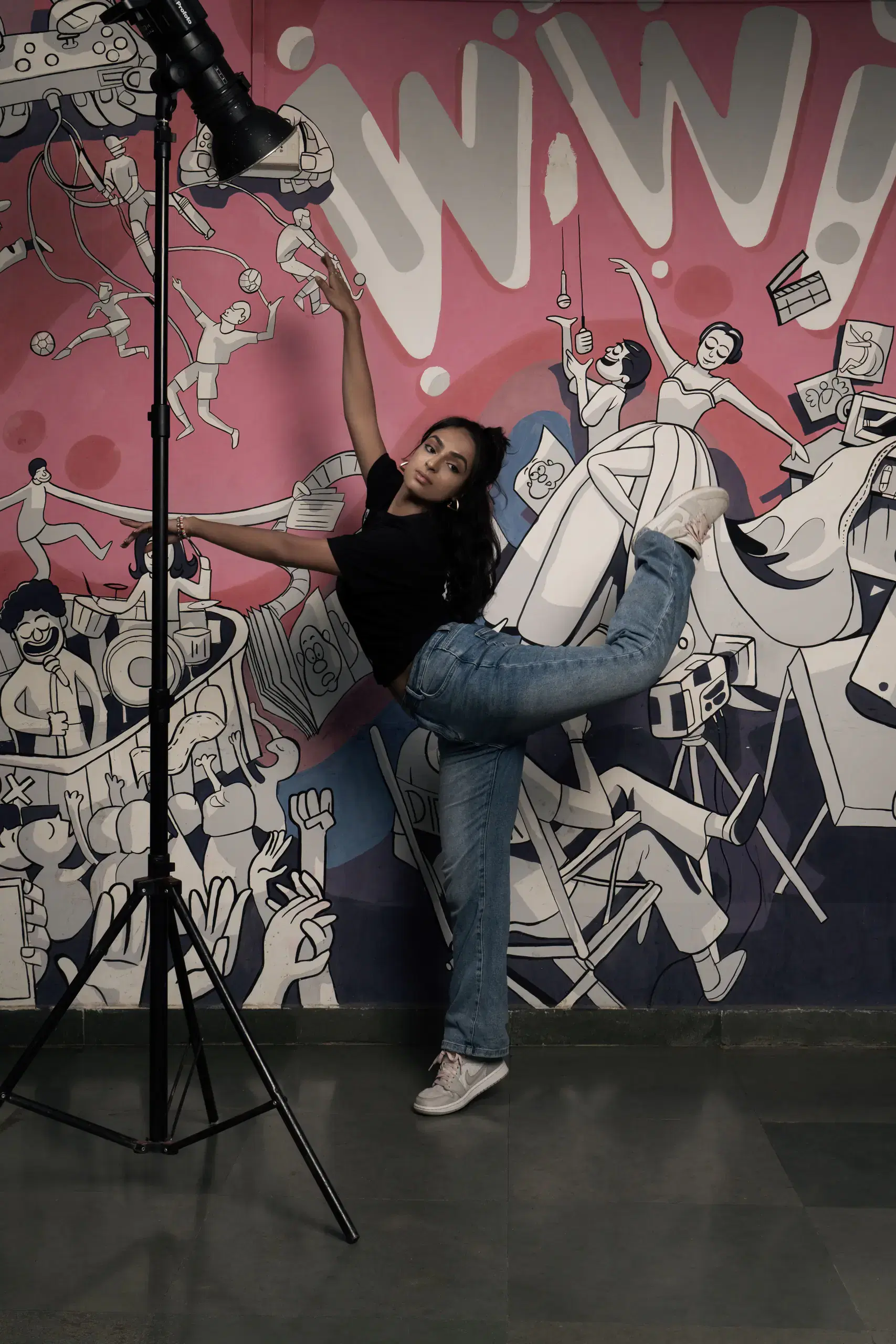 Dance student posing under studio lights in front of a mural