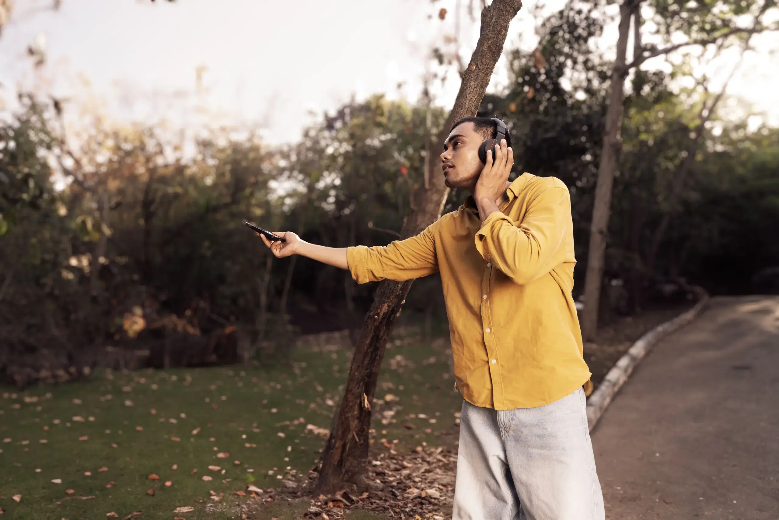 Student recording outdoor sound with headphones and a field recorder