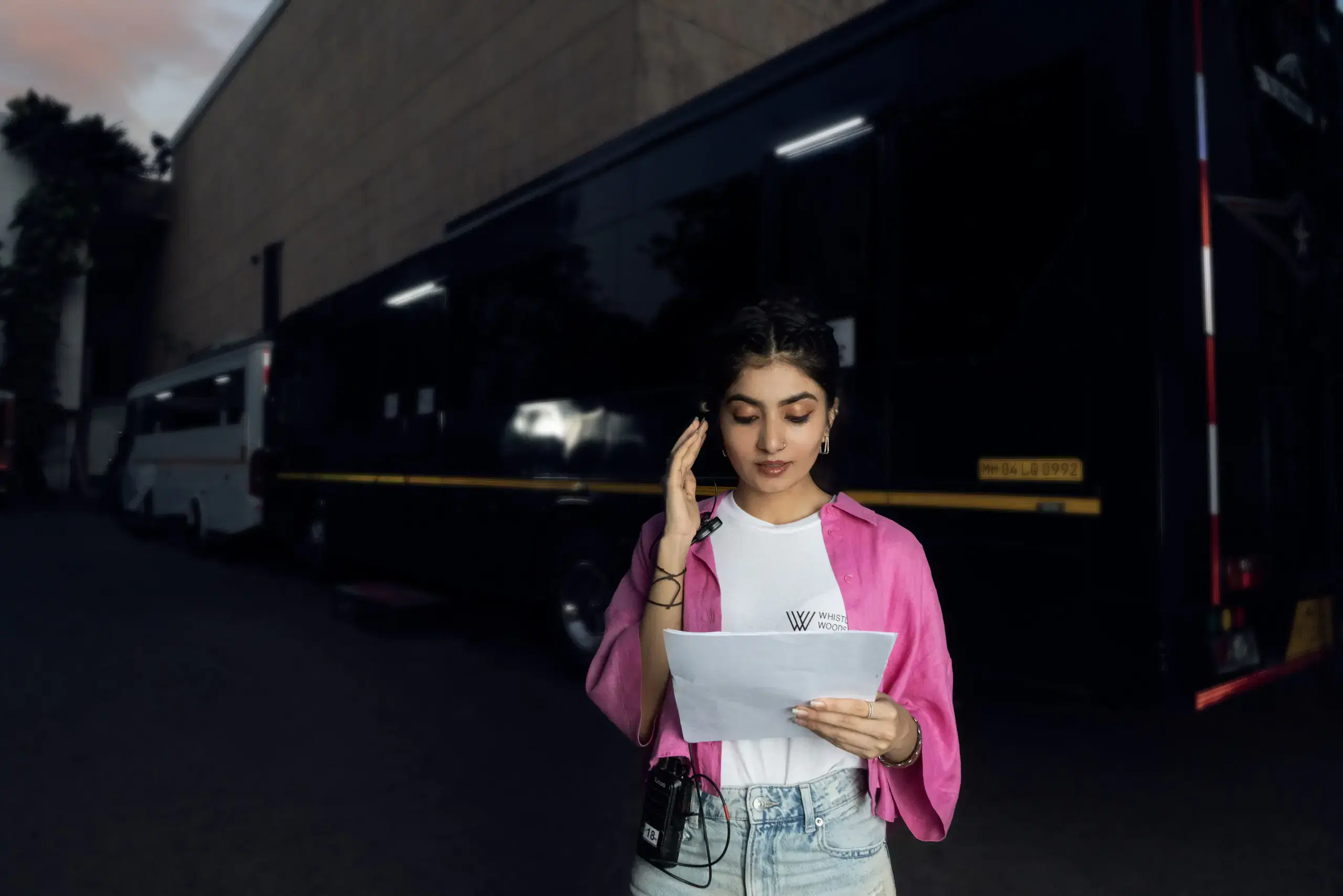 Student reading a script beside production vehicles